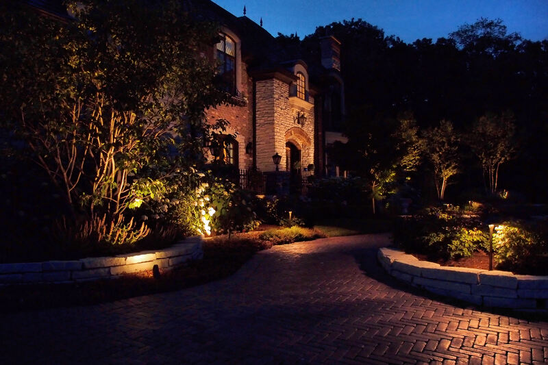 large house and brick driveway illuminated in evening