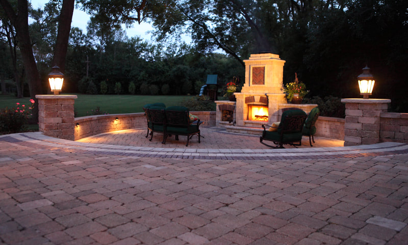 large brick patio with fireplace and chimney at night