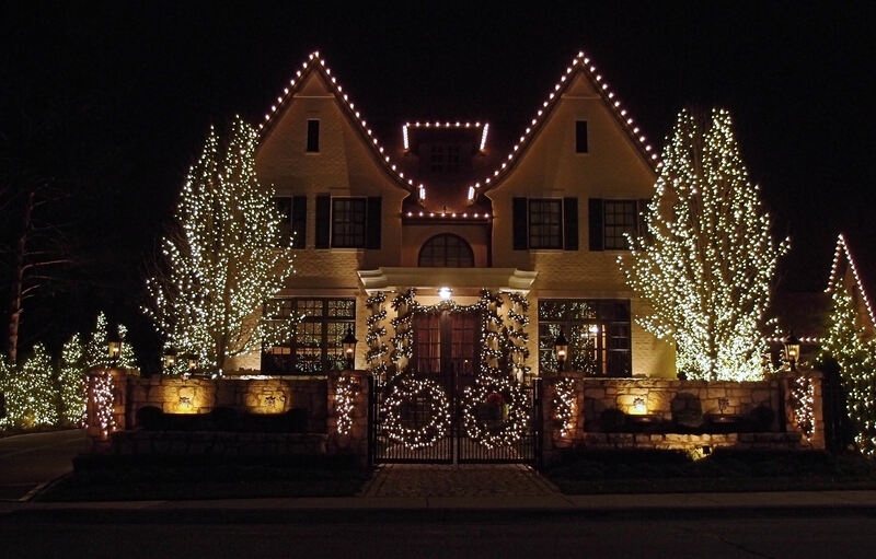 whole facade of home with lights on trees and wreaths